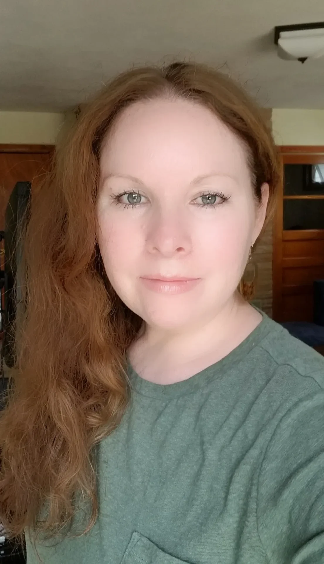 Woman with long red hair wearing a green shirt.