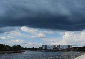 A cloudy sky over the water and buildings.