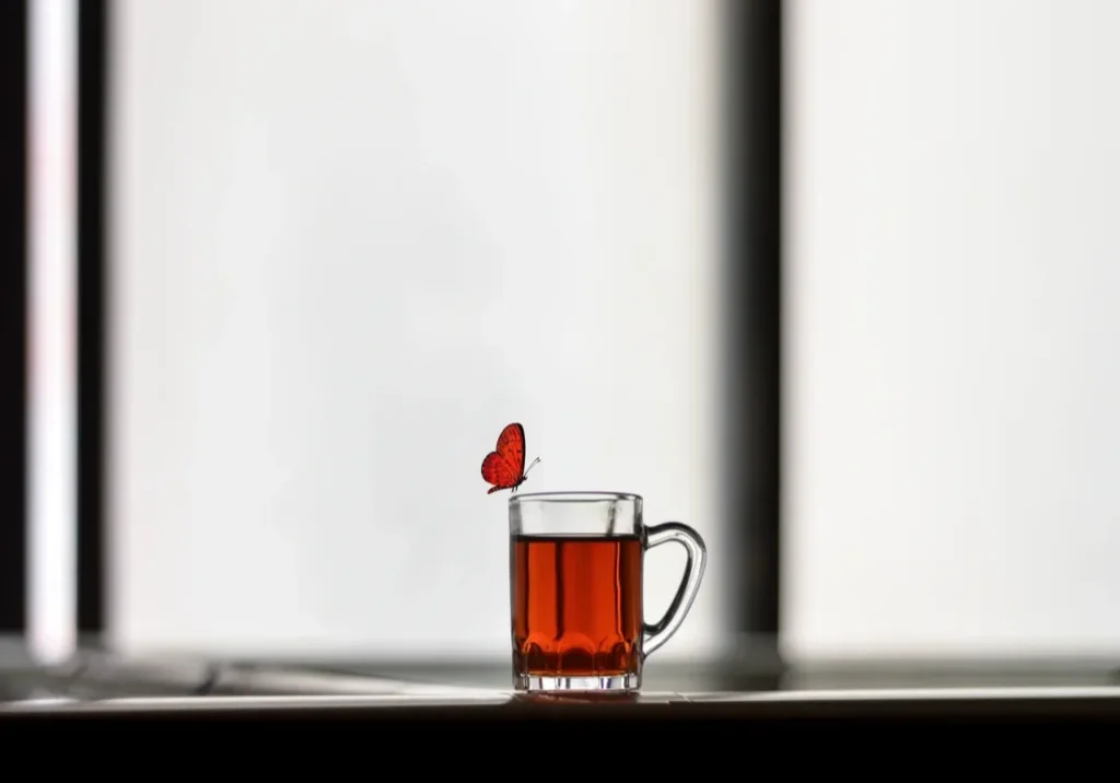 Red butterfly near a glass of tea.