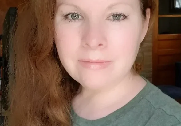 Woman with long red hair wearing a green shirt.